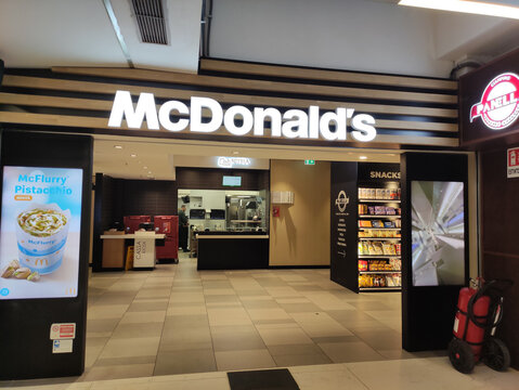 Rome, Italy - January 14, 2026: McDonald's restaurant entrance with illuminated signage, digital menu board displaying McFlurry, and snack vending machine visible in the background