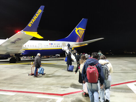 Cagliari, Italy - January 14, 2026: Passengers boarding a Ryanair airplane at night, luggage in tow, with the aircraft's tail and logo clearly visible on the tarmac