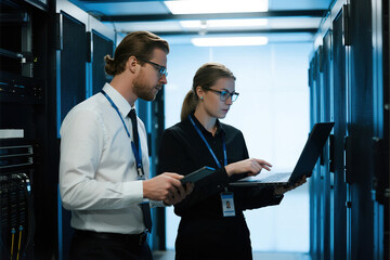 Two IT professionals working in a server room