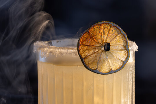 Refreshing smokey margarita with salt on the rim served on ice garnished with a grilled lime wheel.
