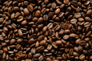 Fototapeta premium Roasted coffee beans background in top view, rich brown texture for cafe branding, menu design, packaging, advertising, and food industry visuals. 