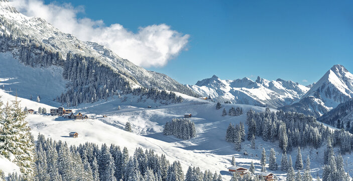 Sunny winter landscape at Lechleiten near Warth Arlberg Austria with alpine chalets hotels at the foot of Biberkopf snow-covered mountains powder slopes and panoramic alpine scenery