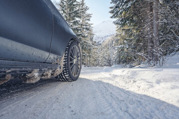 Close-up of a winter tire on a grey metallic car with alloy sport wheels in frog perspective on a...