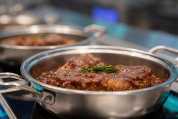 Braised beef rosemary stainless pan rich sauce slow cook kitchen gourmet tender meat comfort food steam rising. Braised beef stainless pan with rich sauce and rosemary, slow cook professional