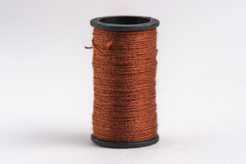 Spool of brown thread on white background closeup.