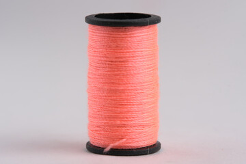 Spool of pink thread on white background, closeup.