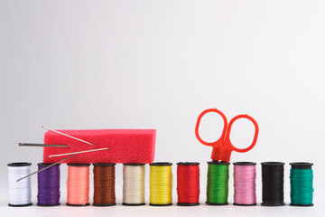 Spools of thread, scissors and needle on white background.