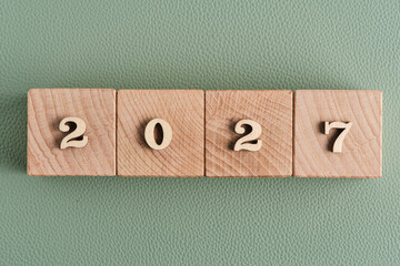 Wooden cubes with year 2027 on green background, New Year concept.