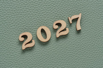 Wooden numbers for 2027 on green leather texture background for New Year concept.