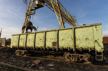 A big hydraulic grab bucket above a train.