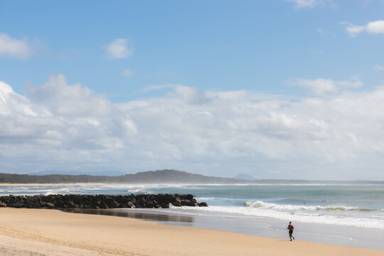 Silhouette of a man jogging a long the sandy shore of Noosa Beach in Noosa Heads, Sunshine Coast, Queensland, Australia.