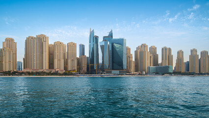 Seaside resort city coastline with skyscrapers, hotels and offices, vacation concept, Dubai Marina, calm sea, blue sky with white clouds