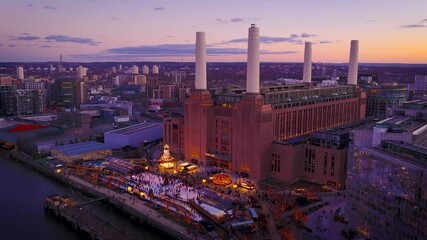 Festive Christmas lights glow around Battersea Power Station beside the Thames at twilight, with London skyline beyond; perfect for holiday travel, real estate and urban branding
