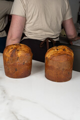 Panettones on a marble countertop with pastry chef in the background_vertical.
