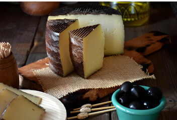 Manchego D.O.P. curado en tabla de madera con aceitunas negras y AOVE © maite