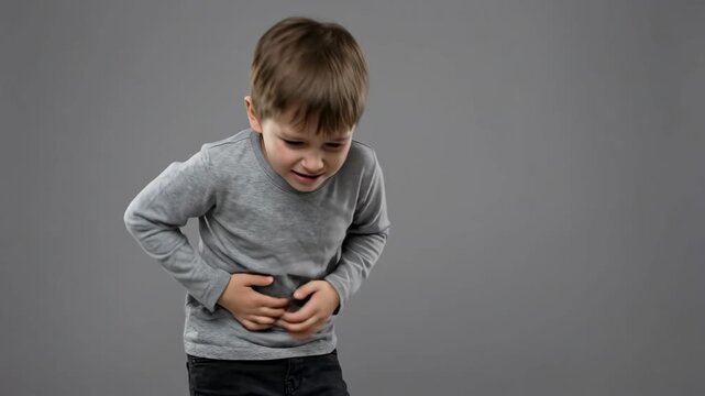 little caucasian boy suffering from strong stomach ache holding belly in pain. unhappy child having health problem. gastritis, food poisoning concept. medical healthcare