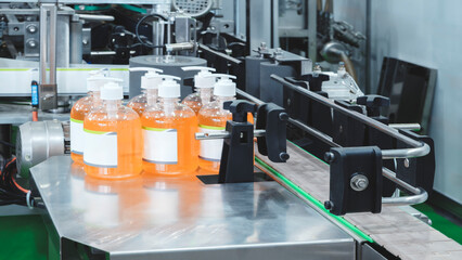 A row of liquid soap bottles on a factory conveyor table. Production and packaging concept.