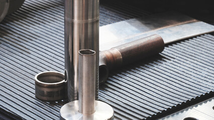 Metal tubes and other parts stand and lie on the work table at the metal processing and industrial plant or factory, industrial concept background.