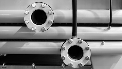 Large white pipes are arranged horizontally as part of a large conduit system, industrial concept