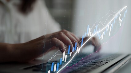 Close-up of hands typing on a laptop, integrated with overlay graphs indicating financial growth. Ideal for themes around data analysis, business productivity, and technology innovation. Copula