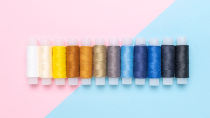 Colorful Spools of Thread Against Pink and Blue Background - Perfect for Sewing and Craft Projects