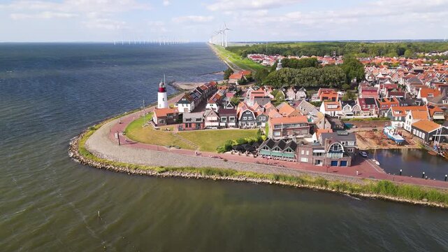 iconic white red topped lighthouse stands grassy point overlooking ijsselmeer gabled houses offshore wind turbines border village urk netherlands structure nautical navigation 