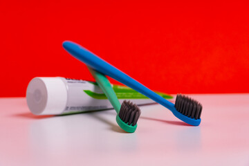 A two toothbrush with toothpaste on red background with copy space, close-up. Dental oral hygiene concept