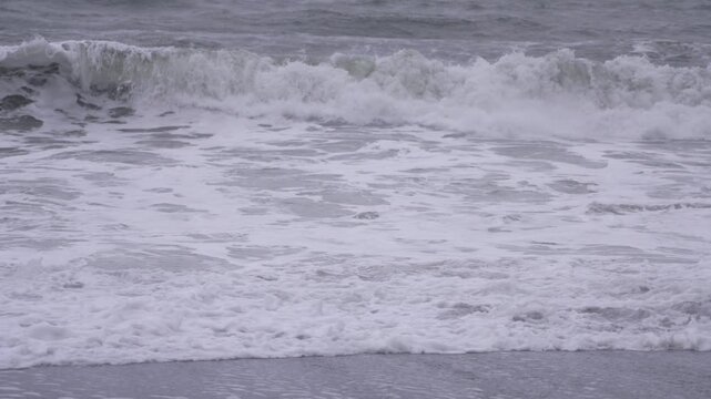 Waves crash on black sand beach in Vik, Iceland at dusk