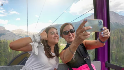 Fototapete Gondeln Smiling mom and daughter selfie on a gondola surrounded by beautiful views  © jovannig