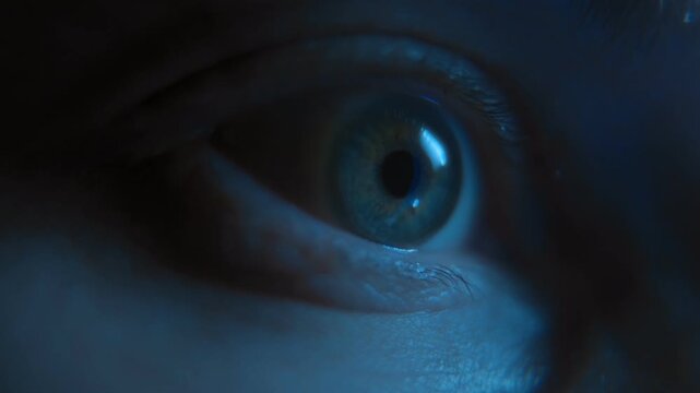 Macro view of a nervous human eye looking at display, illuminated by blue smartphone screen light, representing anxiety, social media addiction, and late-night doom scrolling.