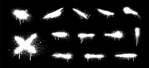 Set of white graffiti spray paint splashes, drips, and textures isolated on black background. Urban street art design elements. © liubomir118809