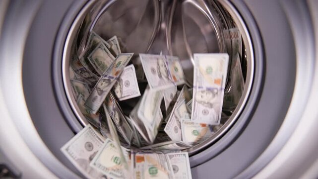 Hundred US Dollar banknotes spinning inside washing machine, slow motion. Money laundering and fraud concept.