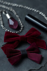 Elegant velvet bow ties and gemstone pendant necklace on dark slate surface
