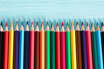 Colored pencils of all colors of the rainbow are on the table.