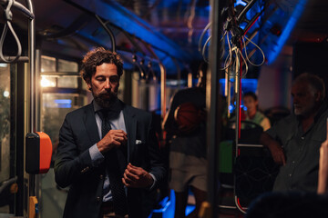Elegant businessman adjusting his jacket on a night bus ride