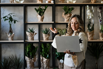 Woman florist working with laptop in small business