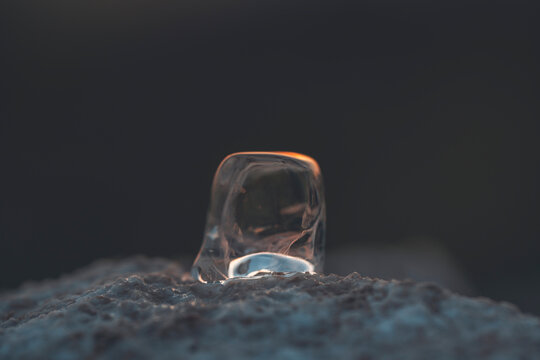 a piece of ice melts on a rock during sunset
