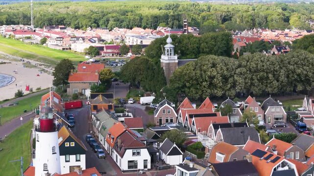 white lighthouse red lantern room stands prominently grassy tip overlooks traditional gabled houses distant forest line urk netherlands tower iconic structure nautical navigation 
