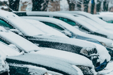 Snowy urban street with parked cars buried under fresh snow, winter weather conditions, cold season...