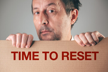 Businessman holding cardboard sign TIME TO RESET motivational concept