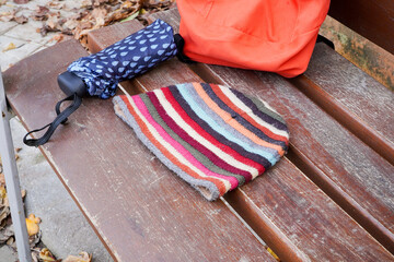 Rainy day essentials on park bench with umbrella and beanie for bad meteorology weather