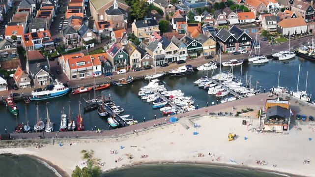 historic sailing vessels motorboats line harbor channel elevated colorful traditional houses sandy beach urk netherlands aerial shot marina nautical navigation yachting 