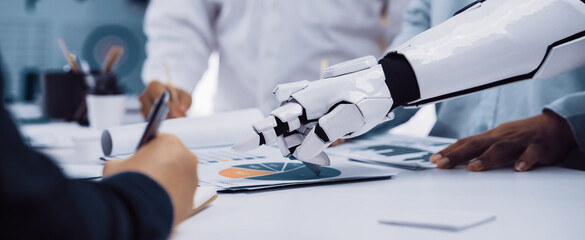 A robotic arm aids a business team in analyzing data and preparing reports, showcasing the integration of advanced technology in a collaborative office setting.Noogenesis