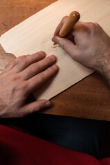 The master carves the center of the Scandinavian pattern on a fir board