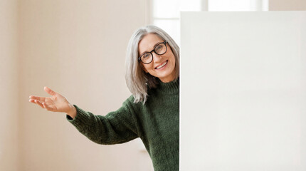 Smiling senior woman presenting white blank board with copy space