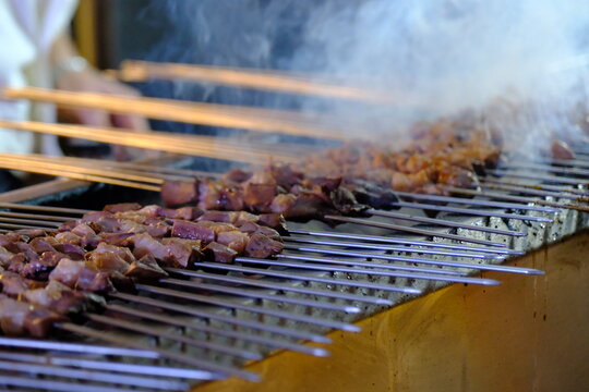 Close-up view of liver kebabs on skewers cooked over a wood fire in a kebab shop. Liver skewers grilled with tail fat . Turkish skewer kebab.