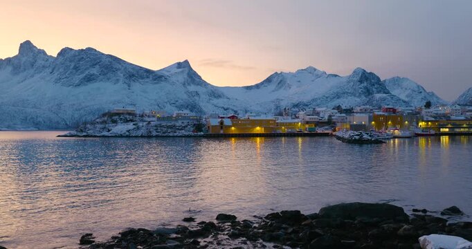 Hus&oslash;y im Winter zur blauen Stunde mit Blick in den Hafen, schneebedeckte H&auml;user und Boote im ruhigen Fjord, kalte Abendstimmung und klares arktisches Licht in Nordnorwegen