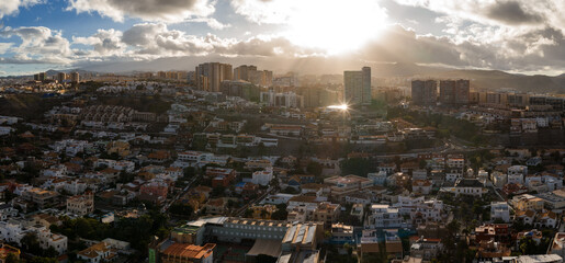Aerial view of Las Palmas de Gran Canaria shows layered hills, a slender tower, high rises, and...