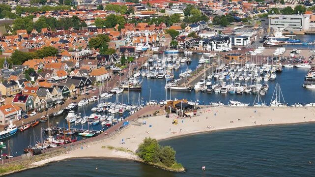 white sailboats motorboats moored organized docks central paved pier elevated sunlit harbor sandy beach urk netherlands near view flevoland marina yachting nautical navigation 