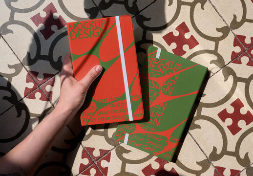 Front and back cover Notebooks are held above a decorative tiled floor. PSD template mockup